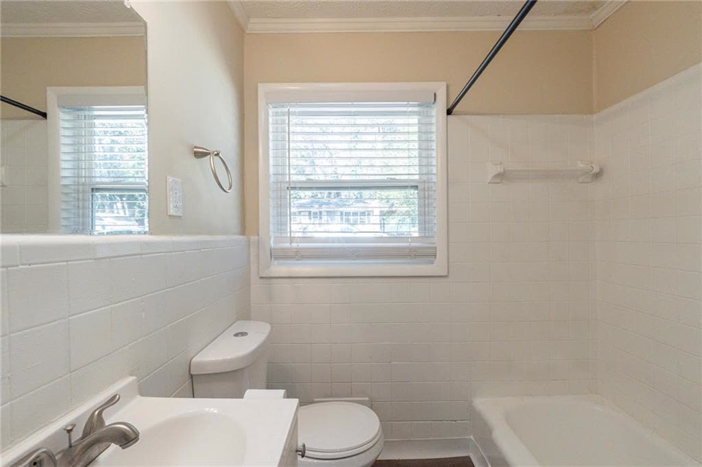 Bathroom with white tile walls, a window, a sink and a tub