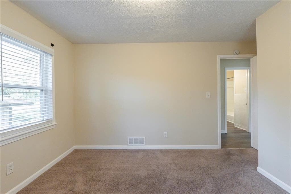 One of the bedrooms, shown empty, with carpet and a window