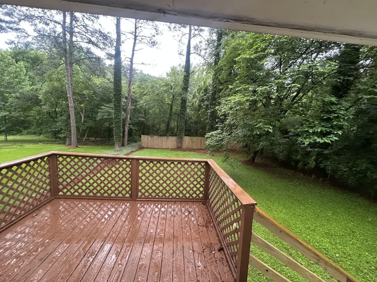 View from the deck across the backyard to the trees and the fence